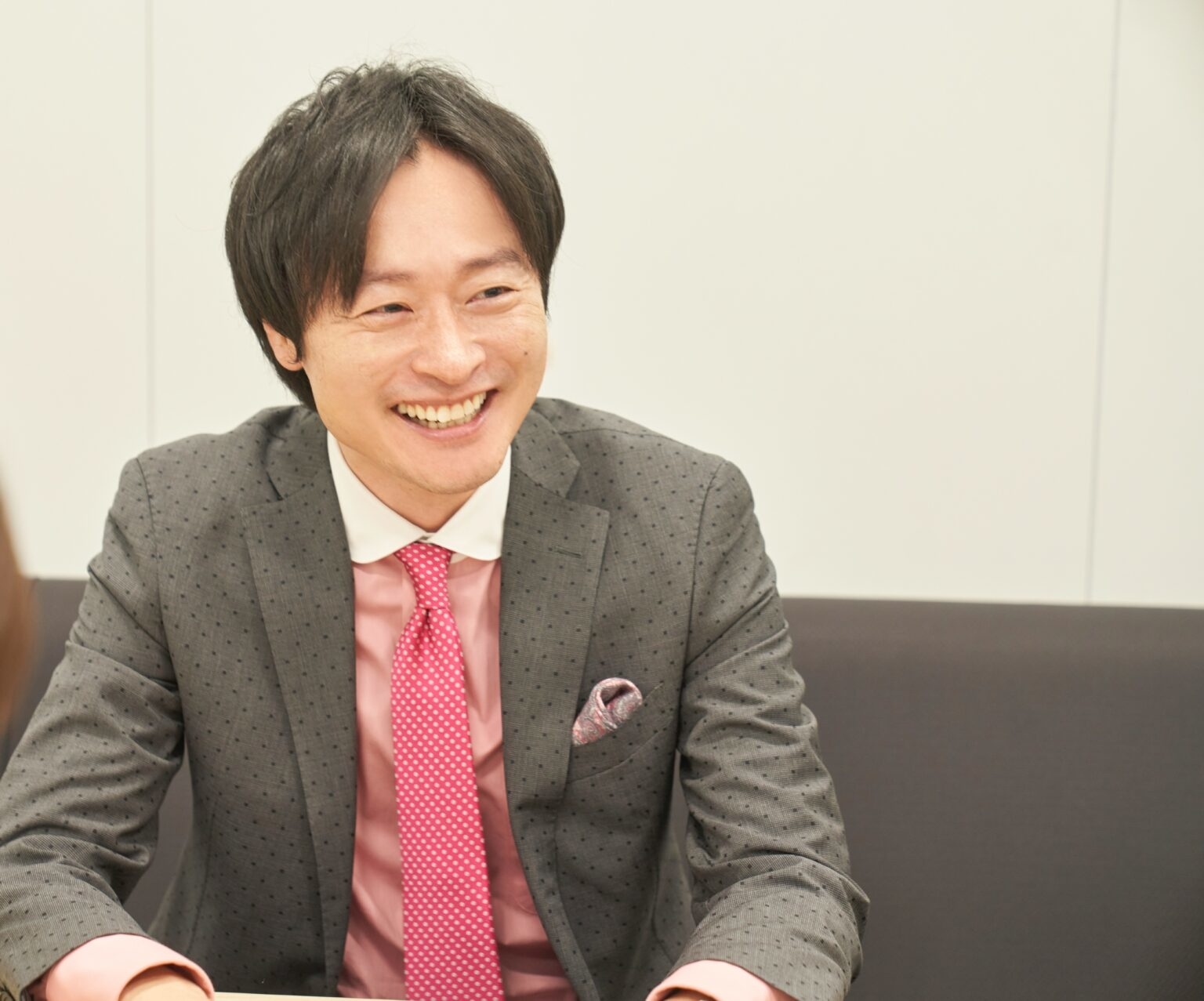 スーツを着た男性が笑顔で座っている