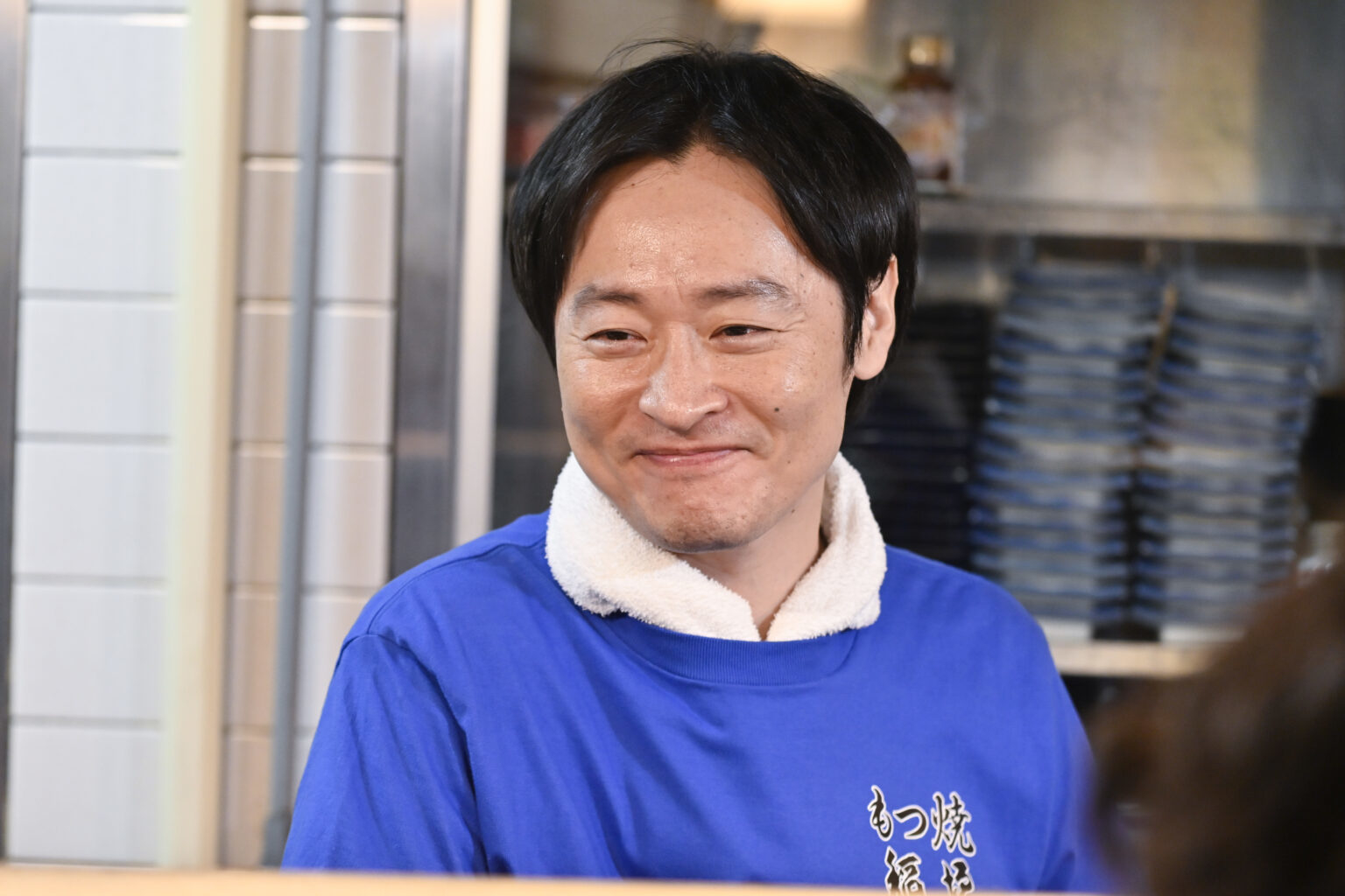 笑顔の男性が青いシャツを着ています。