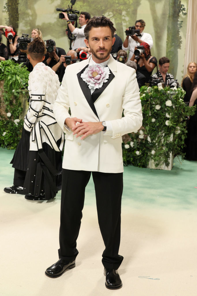 Jonathan Bailey in unique white jacket with floral adornment and black trousers at an event