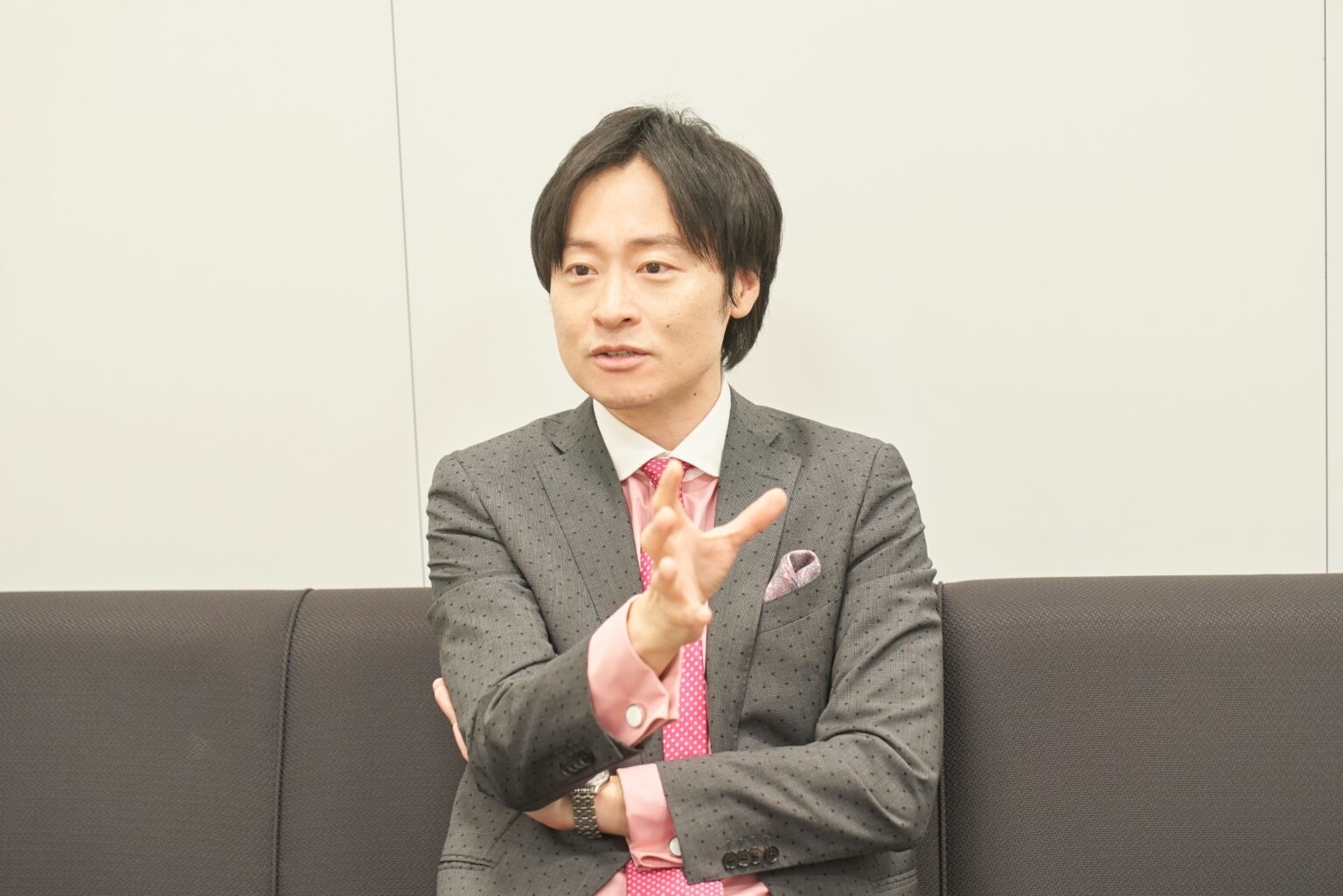 ビジネスマンが会議室で手を組みながら話している様子。