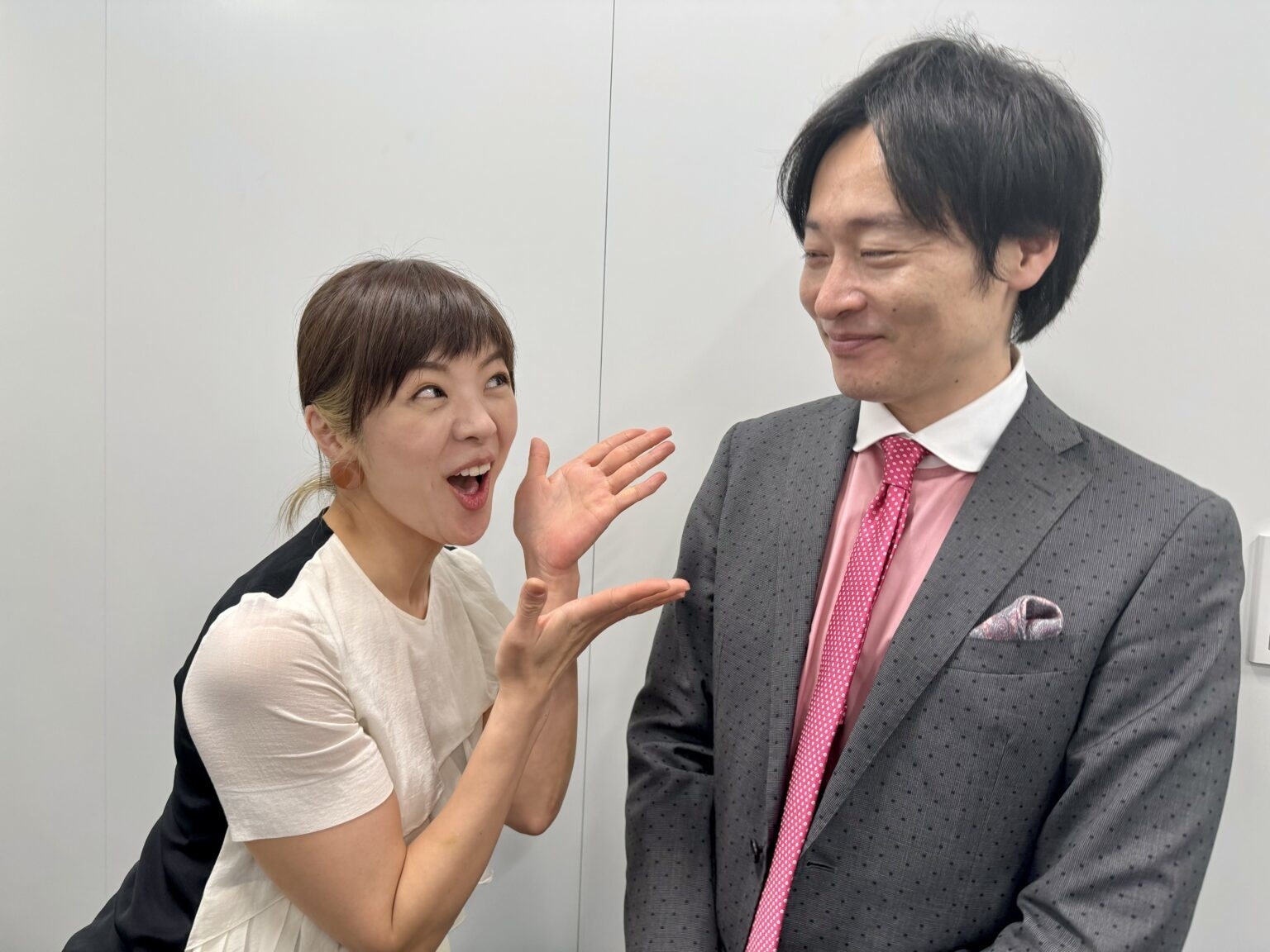 女性が笑顔で男性に話しかけており、男性は微笑んで耳を傾けています。男性はスーツを着用。