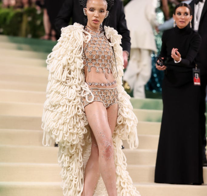 Rihanna in bejeweled outfit and massive fringed coat at event