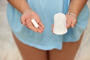Person holding a menstrual pad and tampon, symbolizing choices in feminine hygiene products
