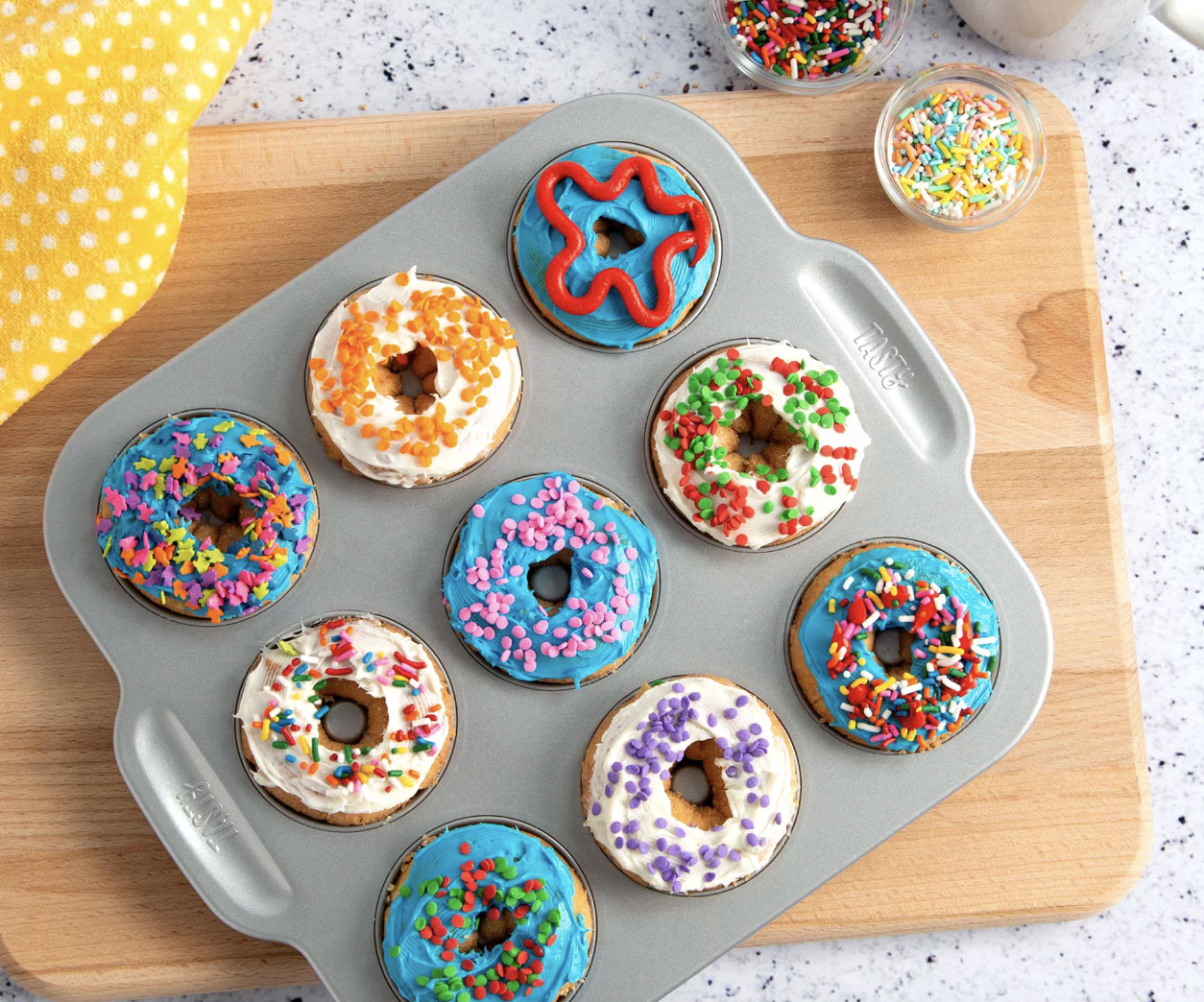 Tray of various decorated doughnuts with assorted sprinkles, displayed for choice or purchase