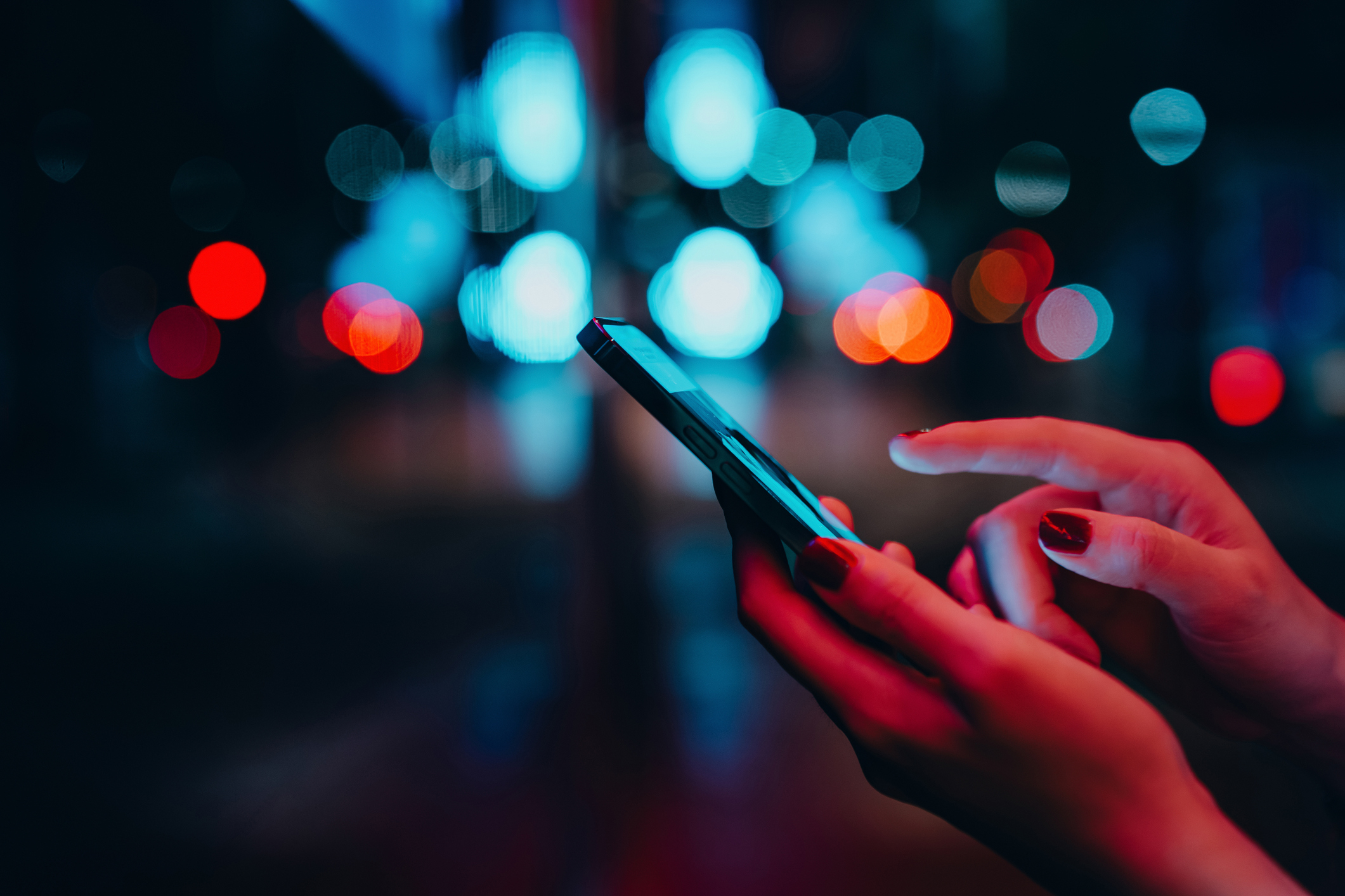 Person using a smartphone at night with blurred lights in the background
