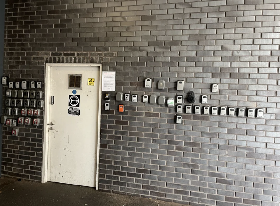 A door with multiple utility meters on a brick wall. A notice is posted beside the door