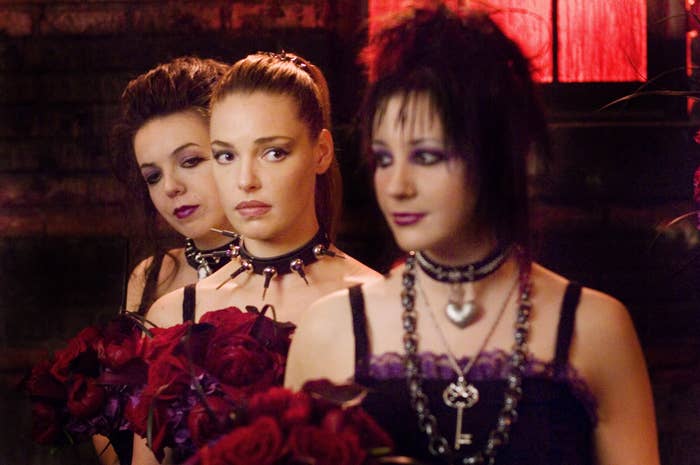 Three bridesmaids in gothic attire holding red roses with Katherine Heigl at the center in 27 Dresses