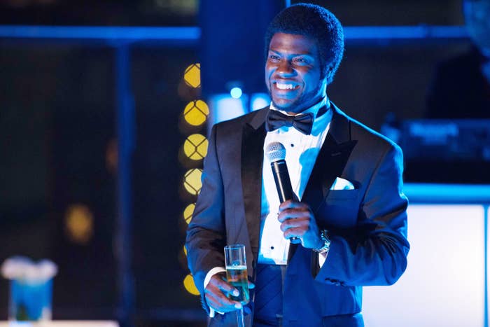 Kevin Hart in a tuxedo with bowtie holding a champagne flute, smiling, at a night event in The Wedding Ringer