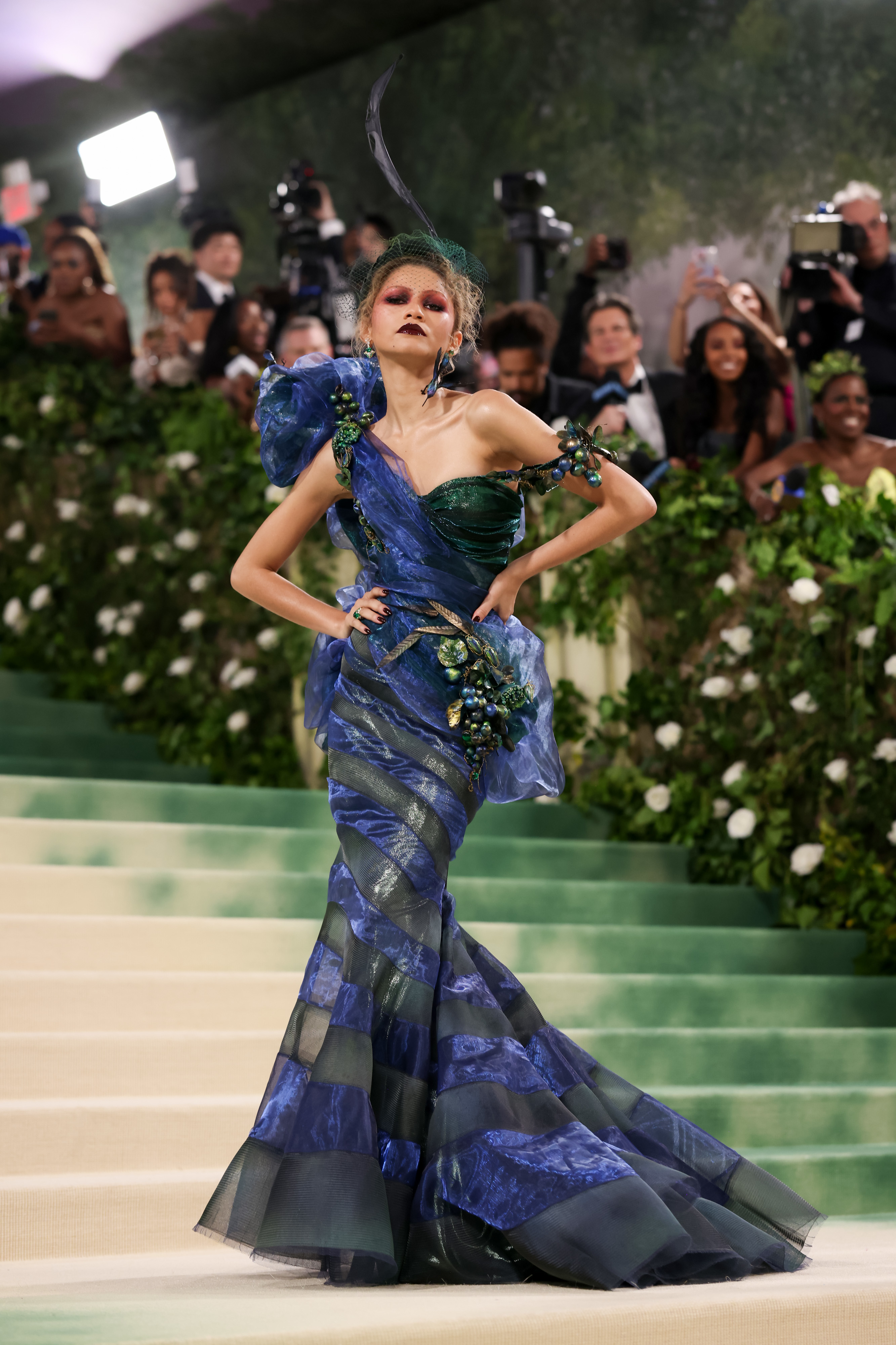 Zendaya in an elaborate blue tiered gown with shoulder embellishments on Met Gala steps