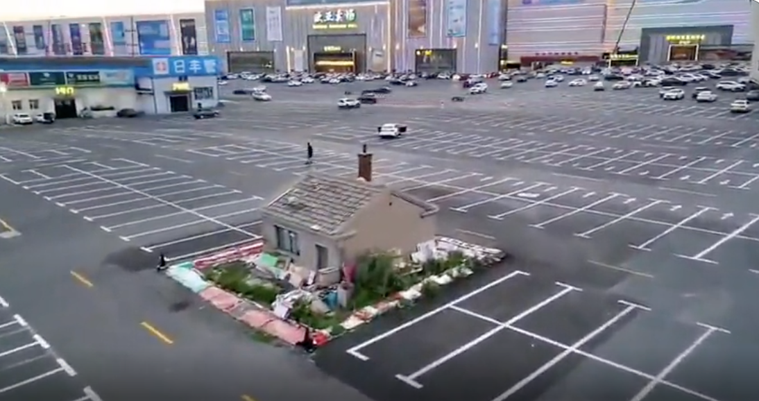 Aerial view of a lone house surrounded by a vast empty parking lot