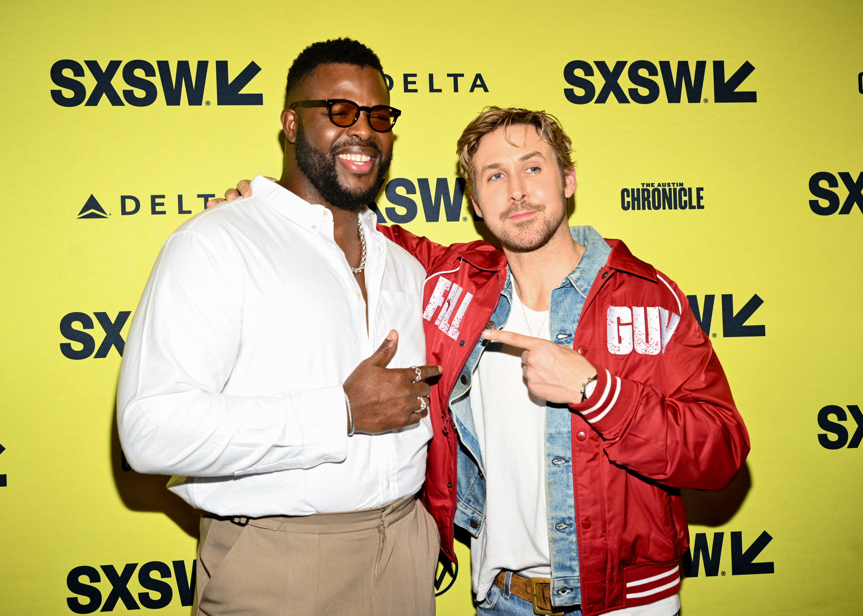 Two men at SXSW event smiling, one in a red jacket with &#x27;GUY&#x27; on it, both pointing at each other