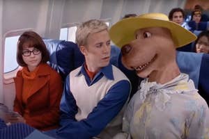 Velma, Fred, and Scooby-Doo, in airplane seats, Scooby wearing a large hat and scarf