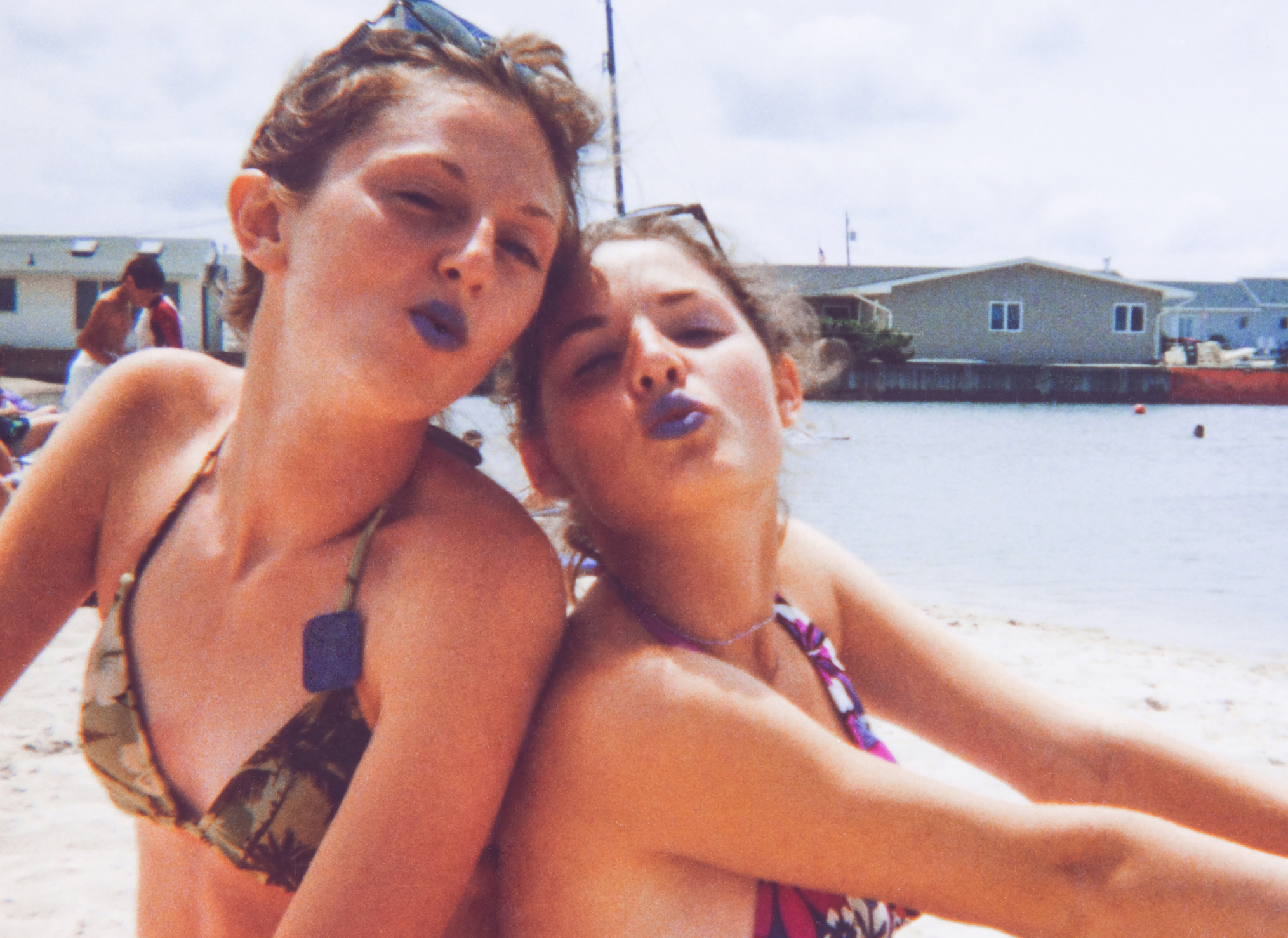 Two individuals posing cheek-to-cheek in swimwear, making playful expressions