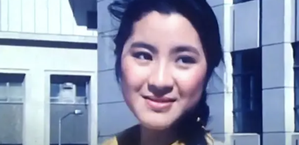 Close-up of Michelle Yeoh smiling with dark hair tied back, wearing a yellow top