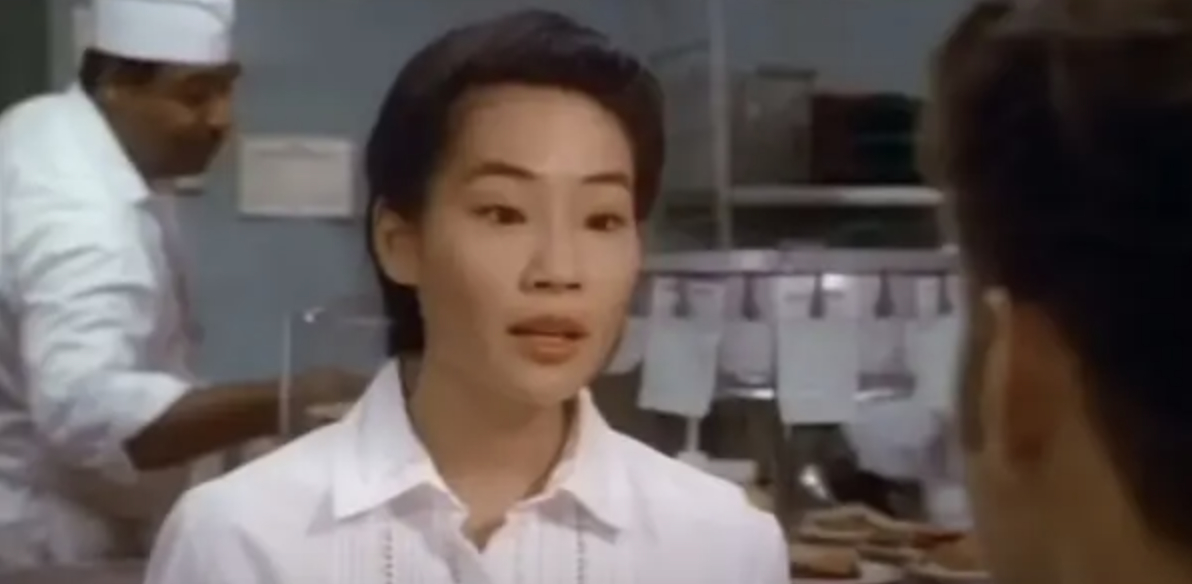 Lucy Liu wearing a white collared shirt in a kitchen setting