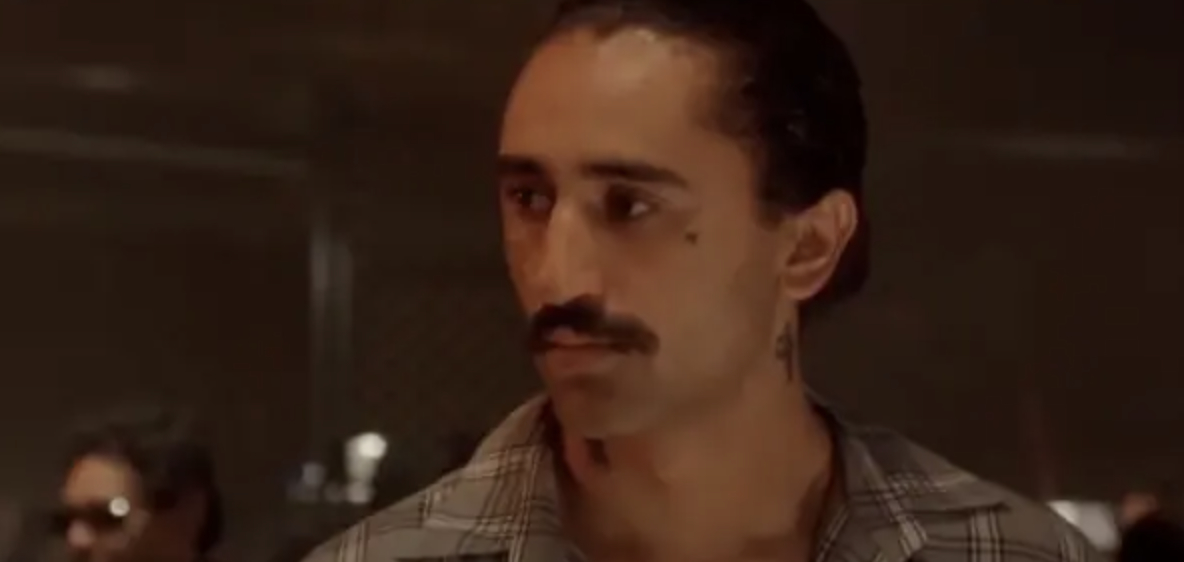 Cliff Curtis with a mustache in a plaid shirt