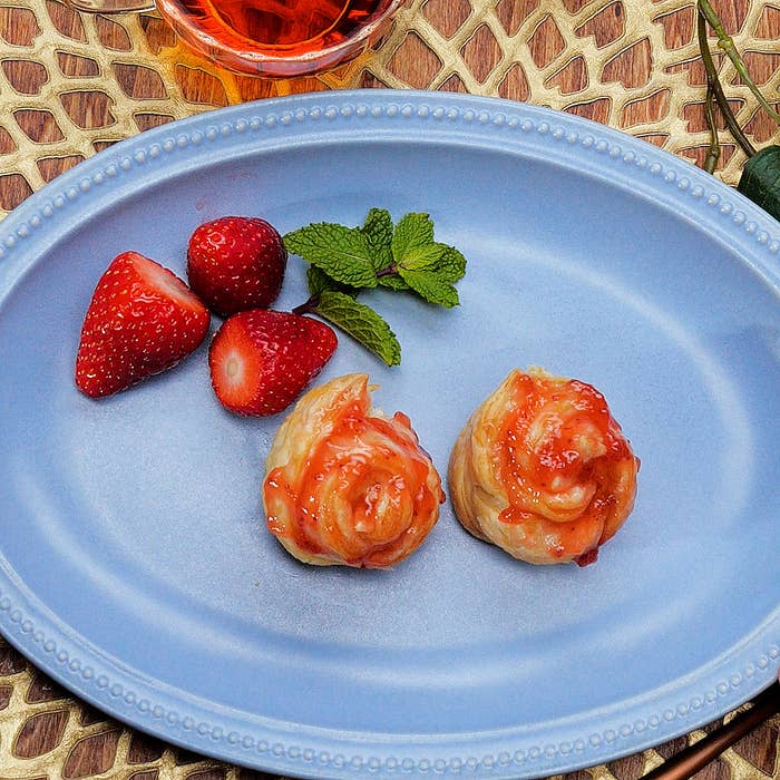 青い皿の上にあるイチゴとミントを添えた2つのジャムを塗ったパイ。