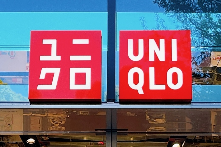 ユニクロ店舗の入り口、ガラス張りのファサードに店名のロゴが掲げられている。