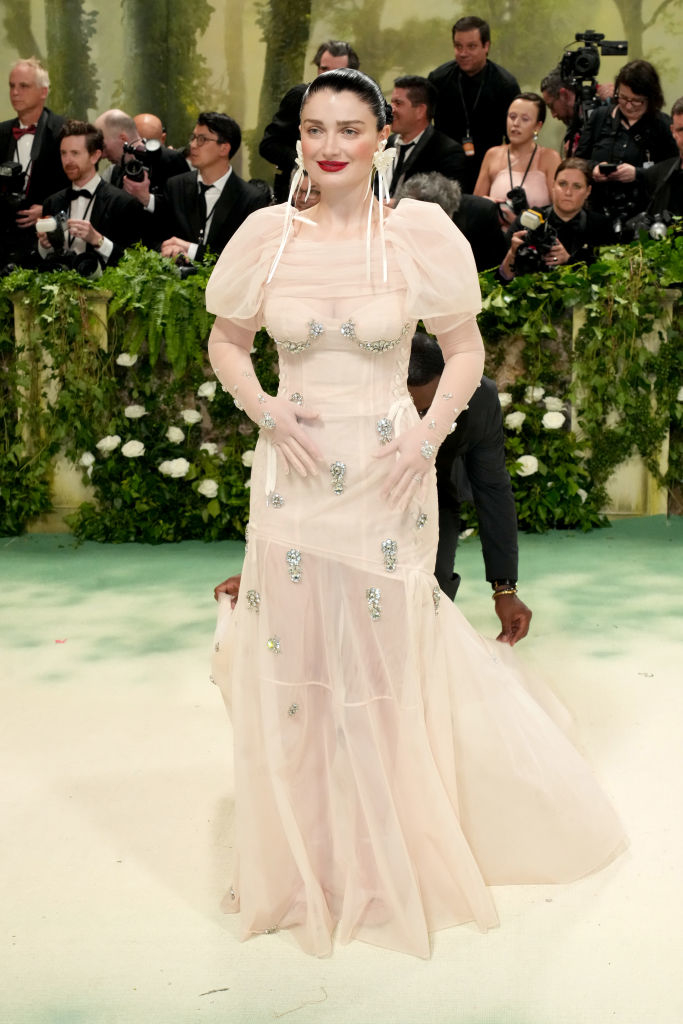 Eve Hewson in a sheer, bejeweled gown with puff sleeves at an event with photographers in background