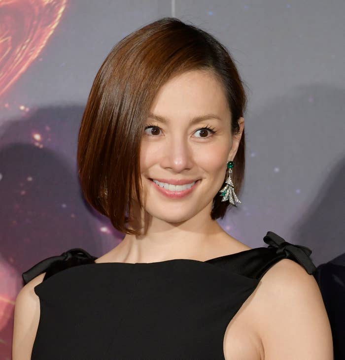 著名な女性がイヤリングをつけ、笑顔でカメラを見ています。