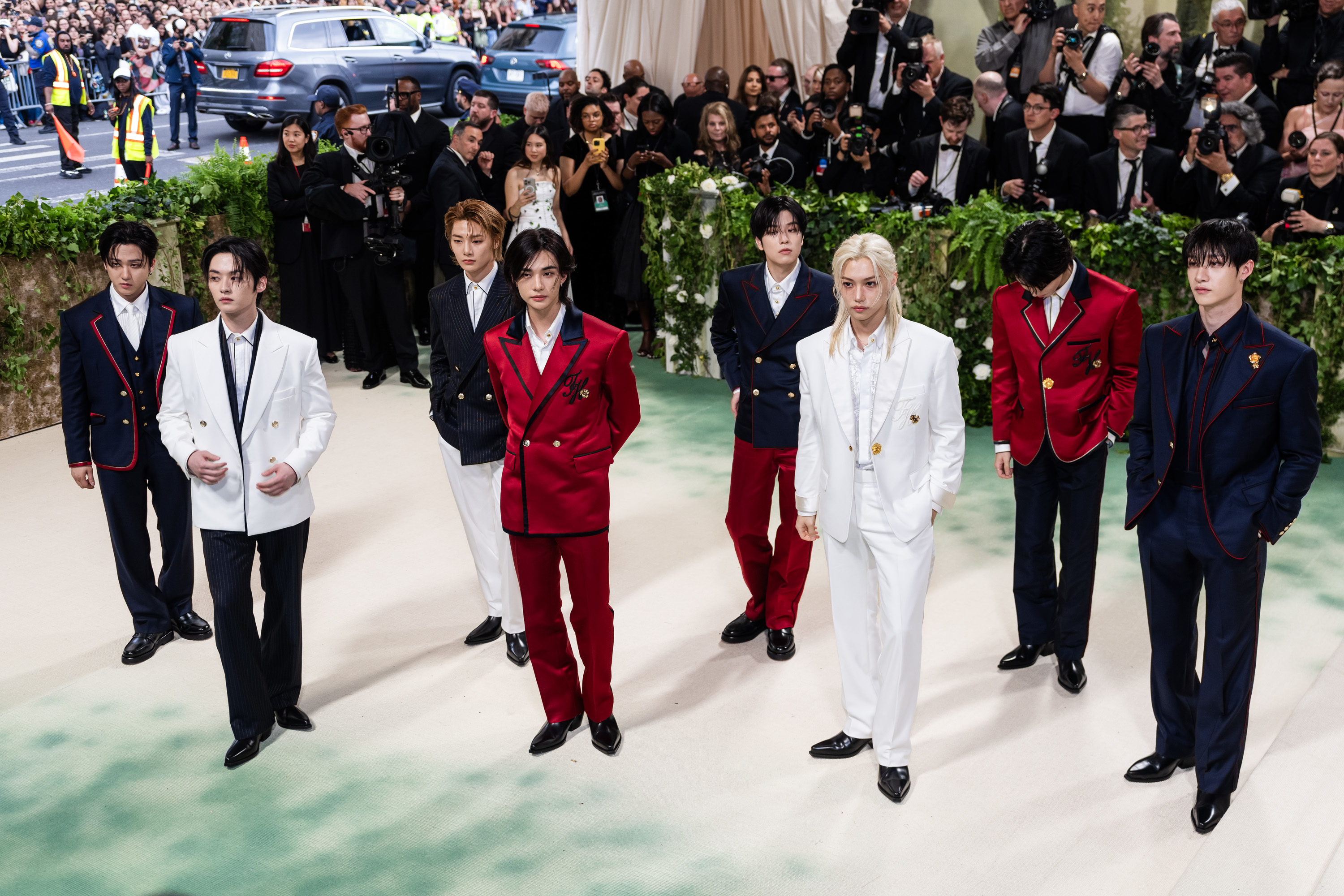 Seven members of BTS in formal suits, walking in line at an event