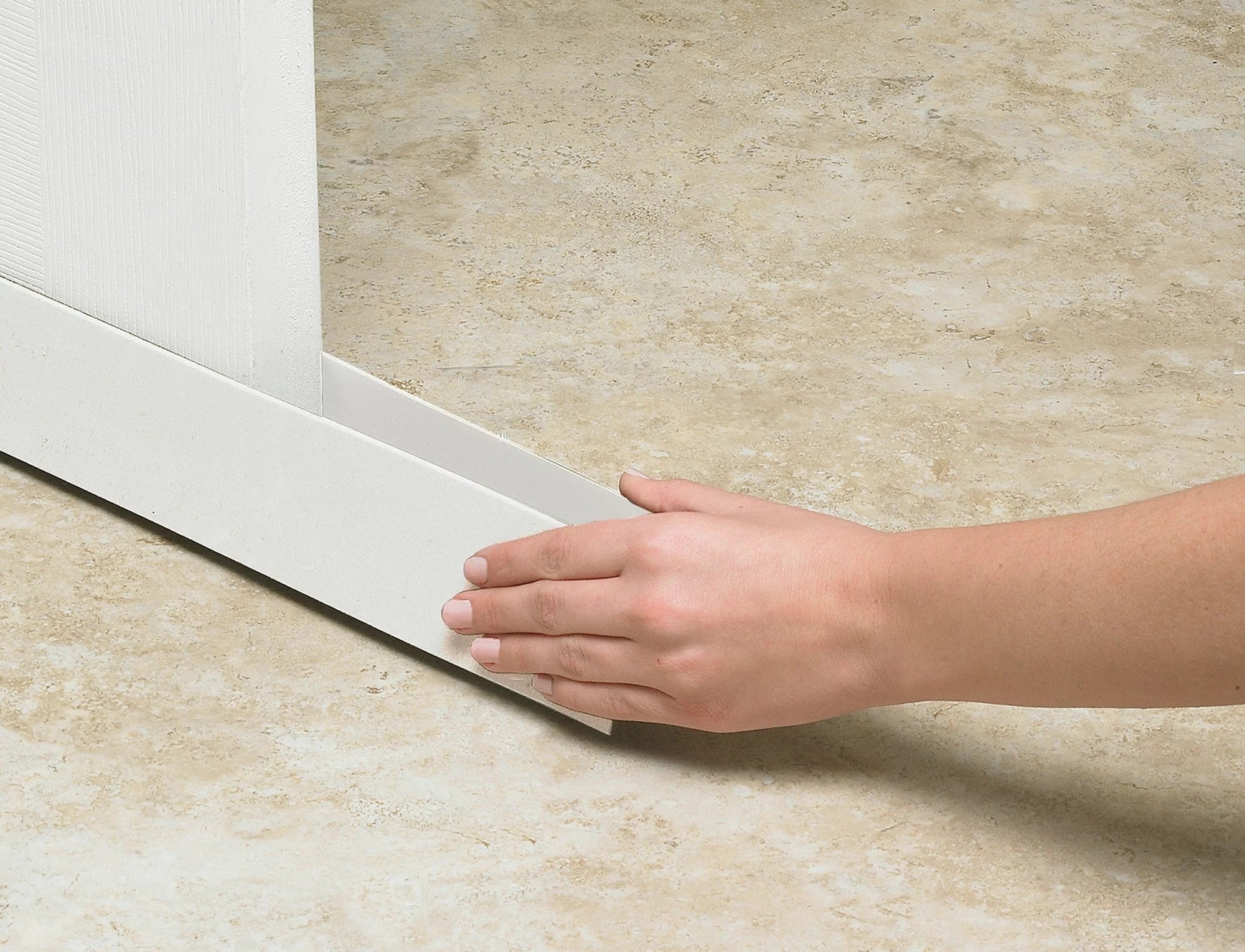 Orang yang memasang white draft stoppers di bagian bawah pintu