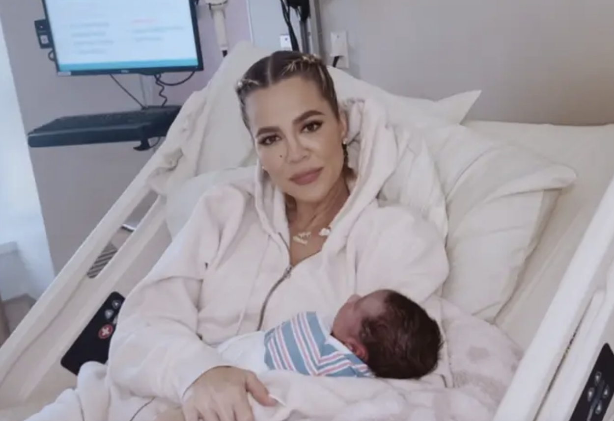 Khloe Kardashian in a hospital bed holding her newborn baby, both are relaxed and content