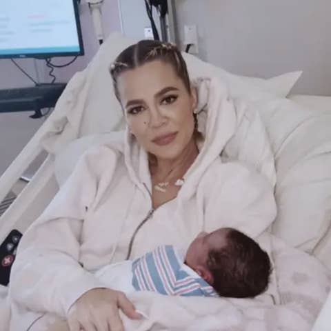 Khloé Kardashian in a hospital bed, holding her newborn baby, looking at the camera