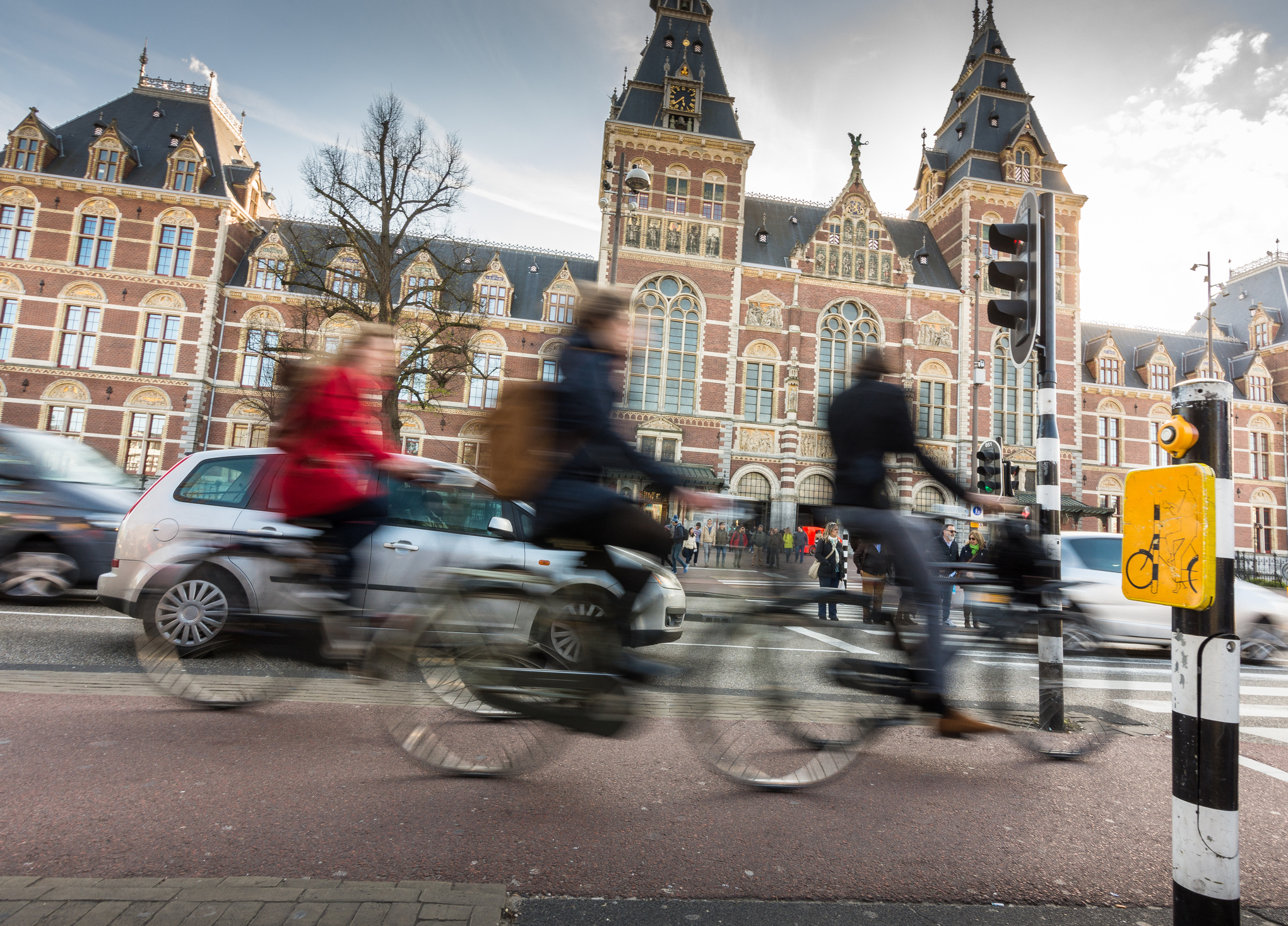 Busy street scene with cyclists and a car, blurred motion, and a building in the background