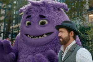 Man in a hat and vest standing with an animated purple character with a wide smile