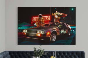 Astronaut exiting a DeLorean under neon lights in a room with a canvas print of the scene on the wall