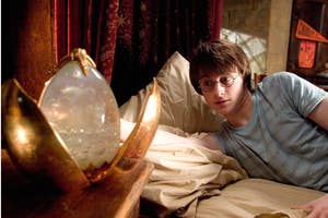 Harry Potter peers curiously at the magical orb, the Prophecy Record, in a dimly lit room