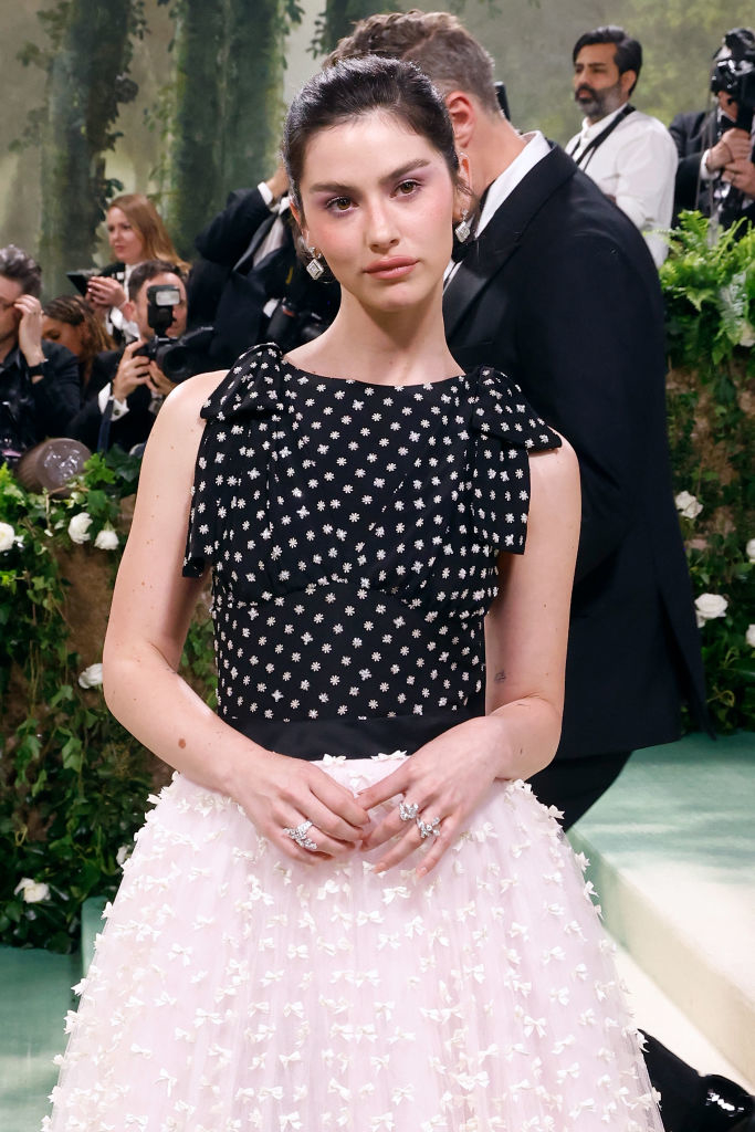 Gracie Abrams in a polka-dot top and detailed skirt poses on steps; photographers in background