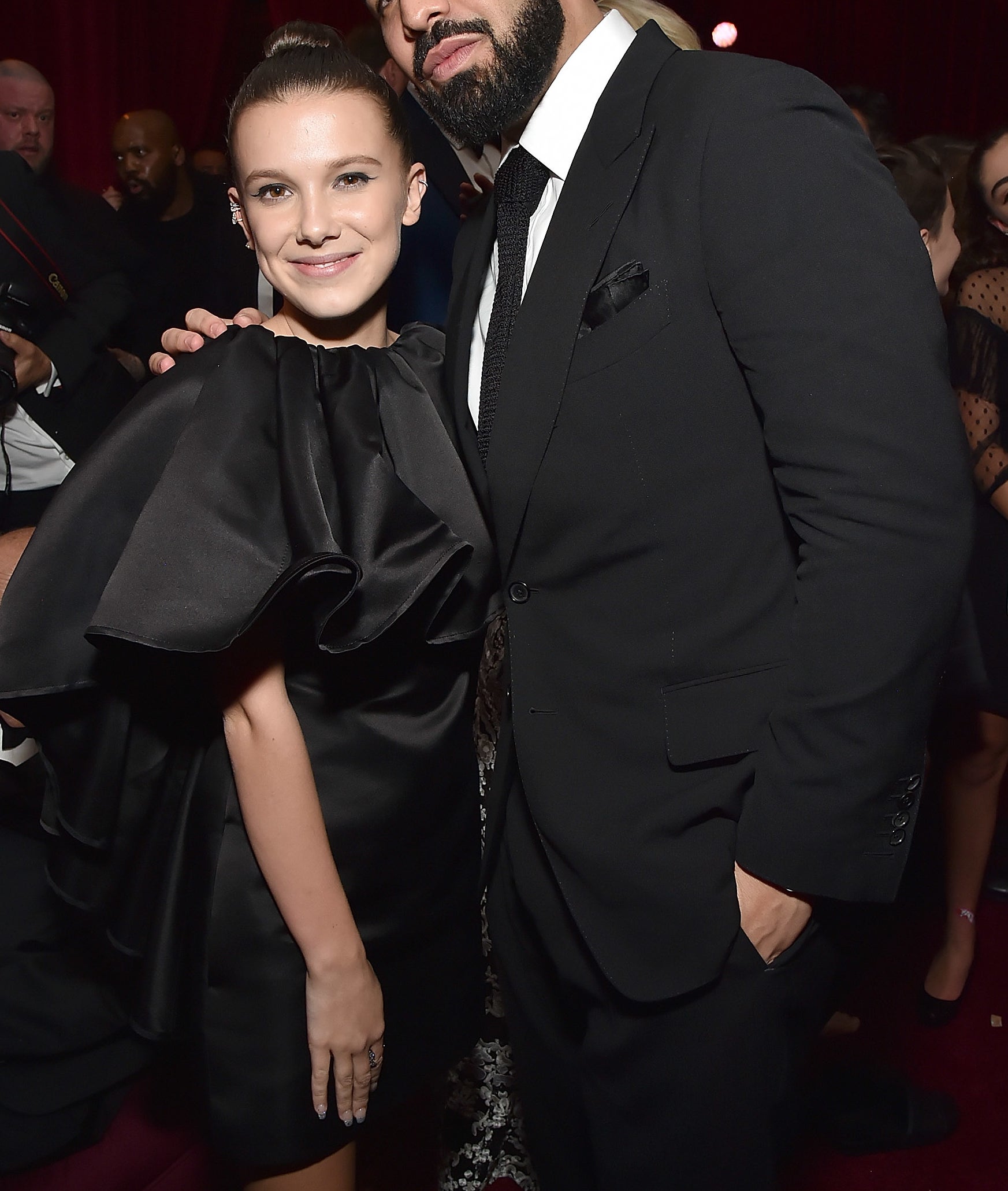Millie Bobby Brown and Drake posing together at an event, both dressed in formal attire