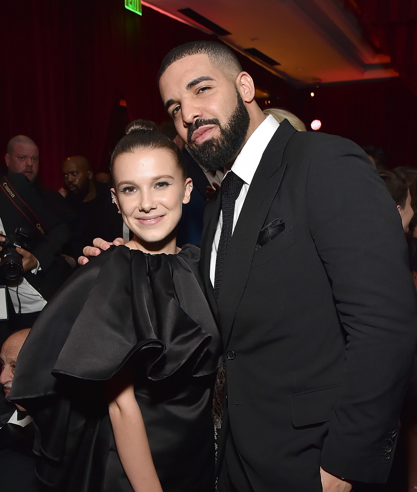 Millie Bobby Brown and Drake posing together at an event, both dressed in formal attire