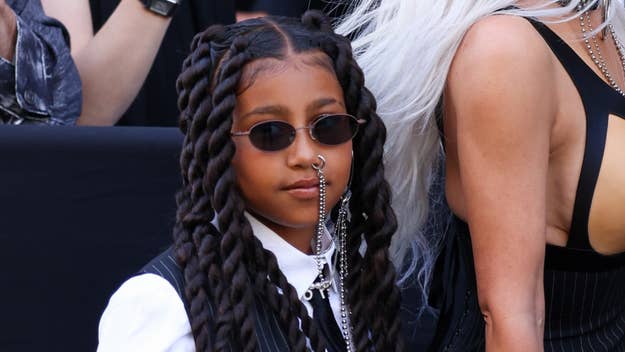 Young girl with braids wearing sunglasses and a white shirt with silver accessories at a public event