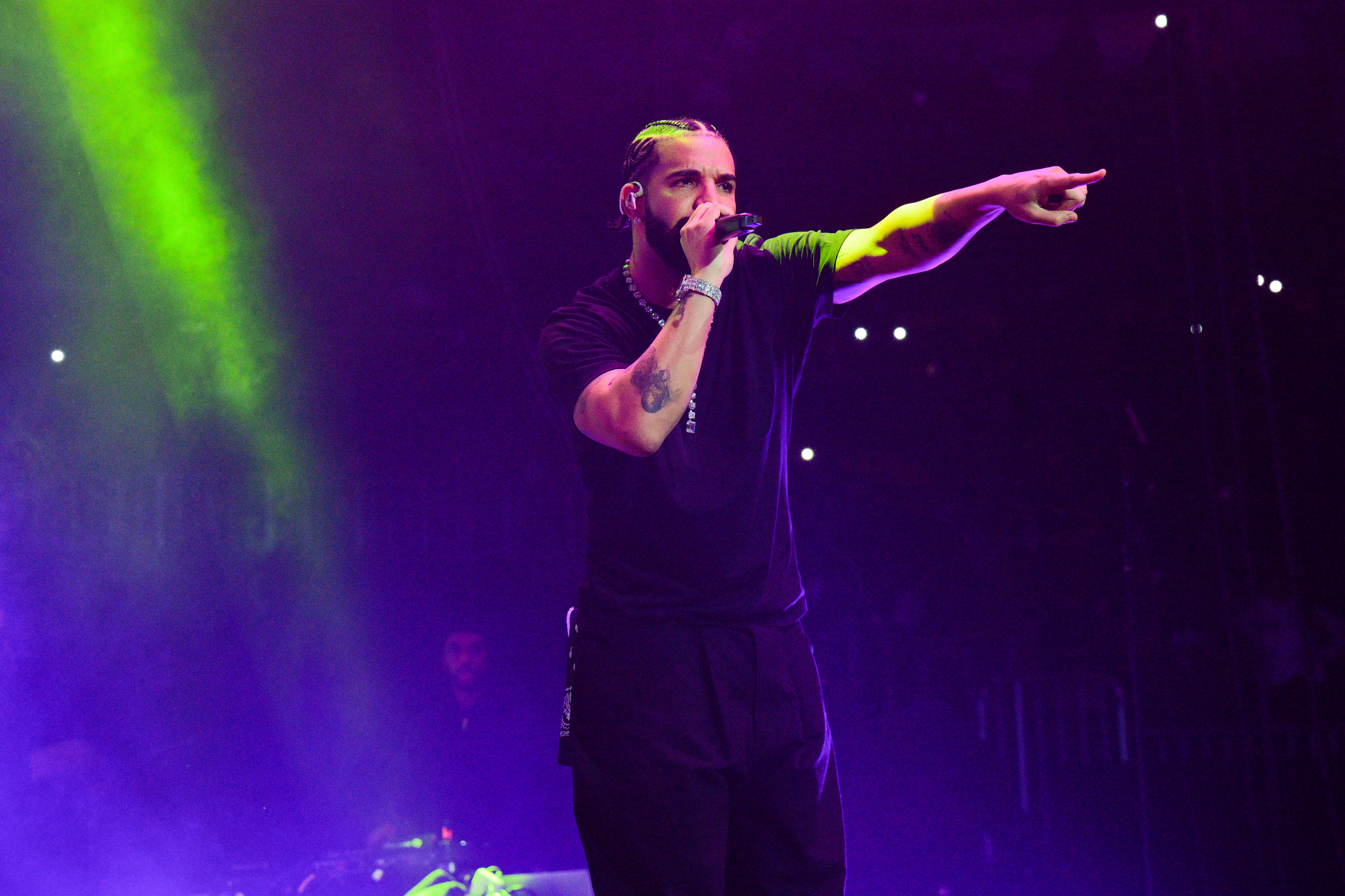 Drake on stage singing and pointing into the audience
