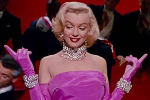 Marilyn Monroe in a pink gown with gloves and pearl jewelry, smiling with closed eyes, in a film scene