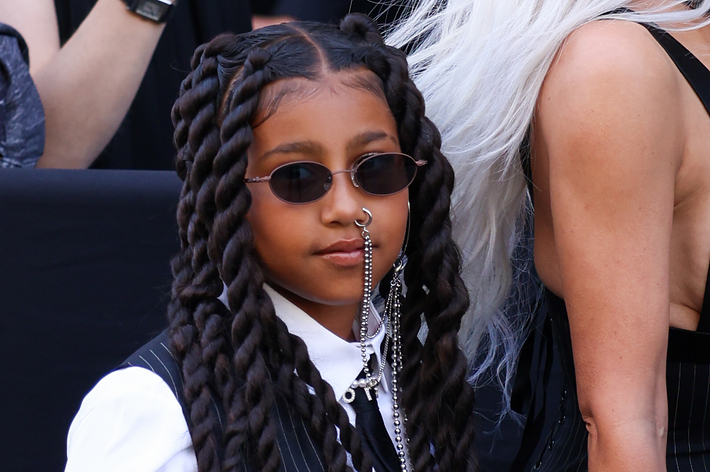 Young girl with braids wearing sunglasses and a white shirt with silver accessories at a public event