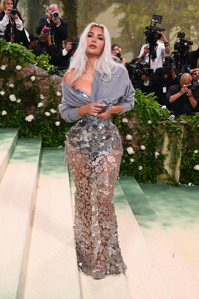 Kim Kardashian in a shimmering gown with photographers in the background