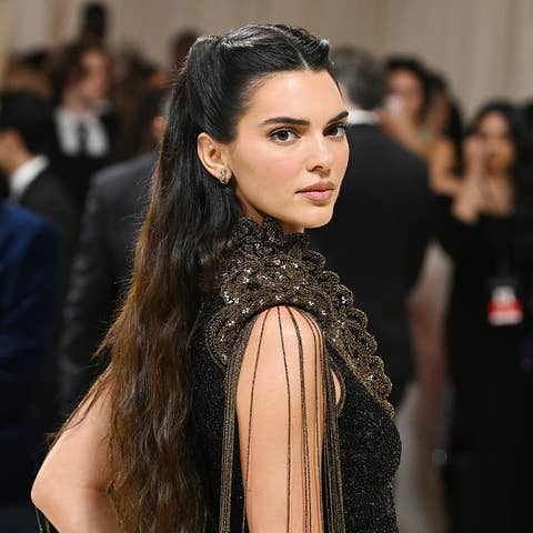 Kendall Jenner in an elegant black lace gown at a formal event. She is looking over her shoulder
