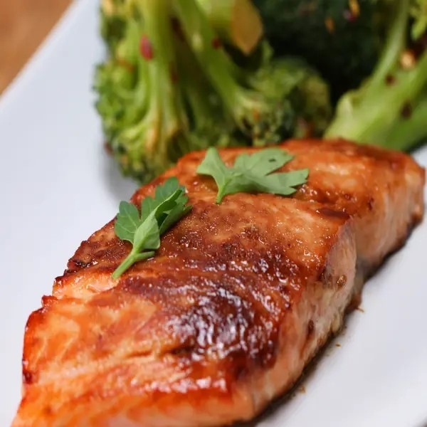 Grilled salmon fillet with a garnish, served with roasted broccoli on a plate