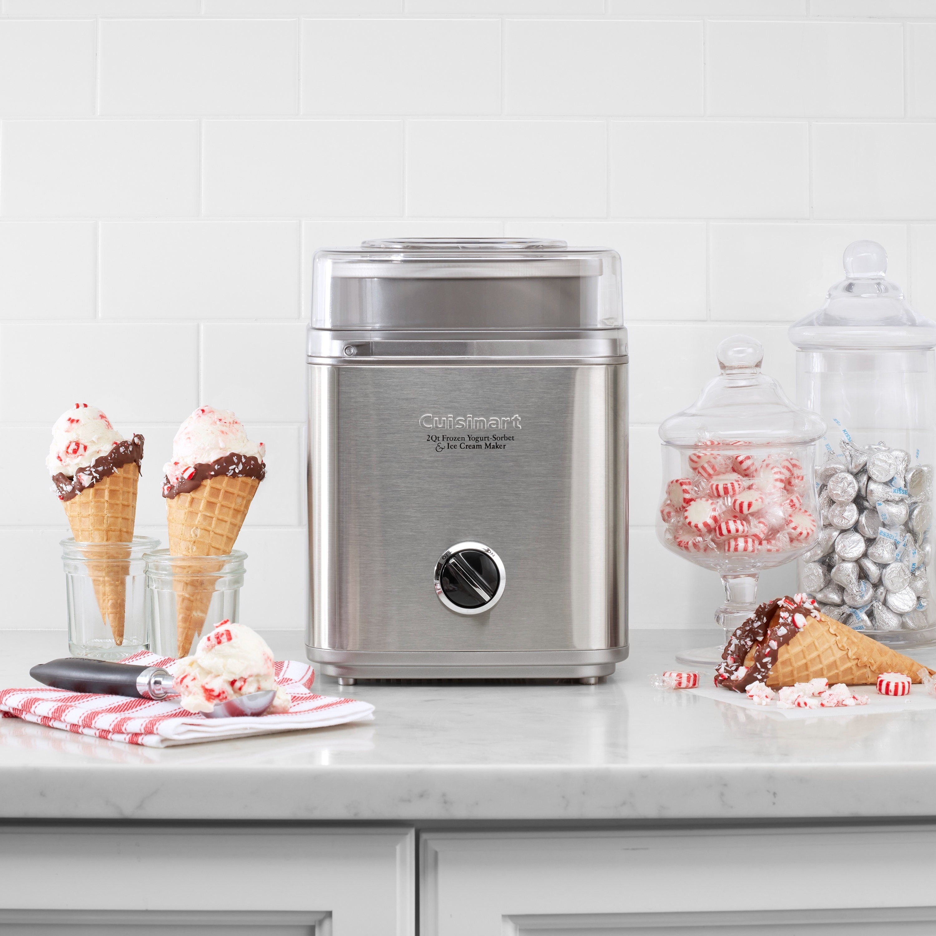 Cuisinart ice cream maker on a counter with two cones filled with scoops of ice cream beside it