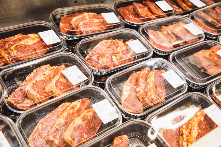 Pre-packaged raw marinated meats displayed for sale in a store