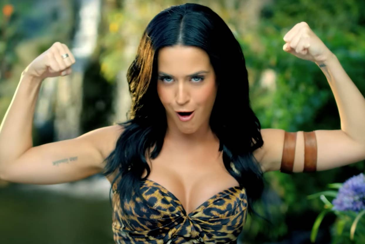 Katy Perry flexing with clenched fists, wearing a leopard print top