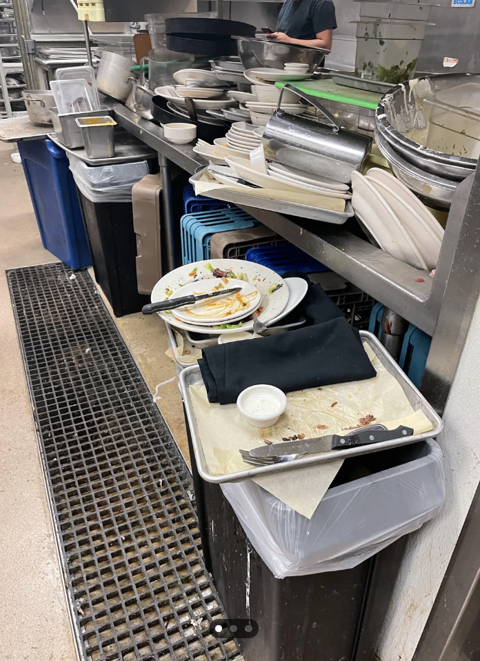 A busy restaurant kitchen with dishes stacked for cleaning