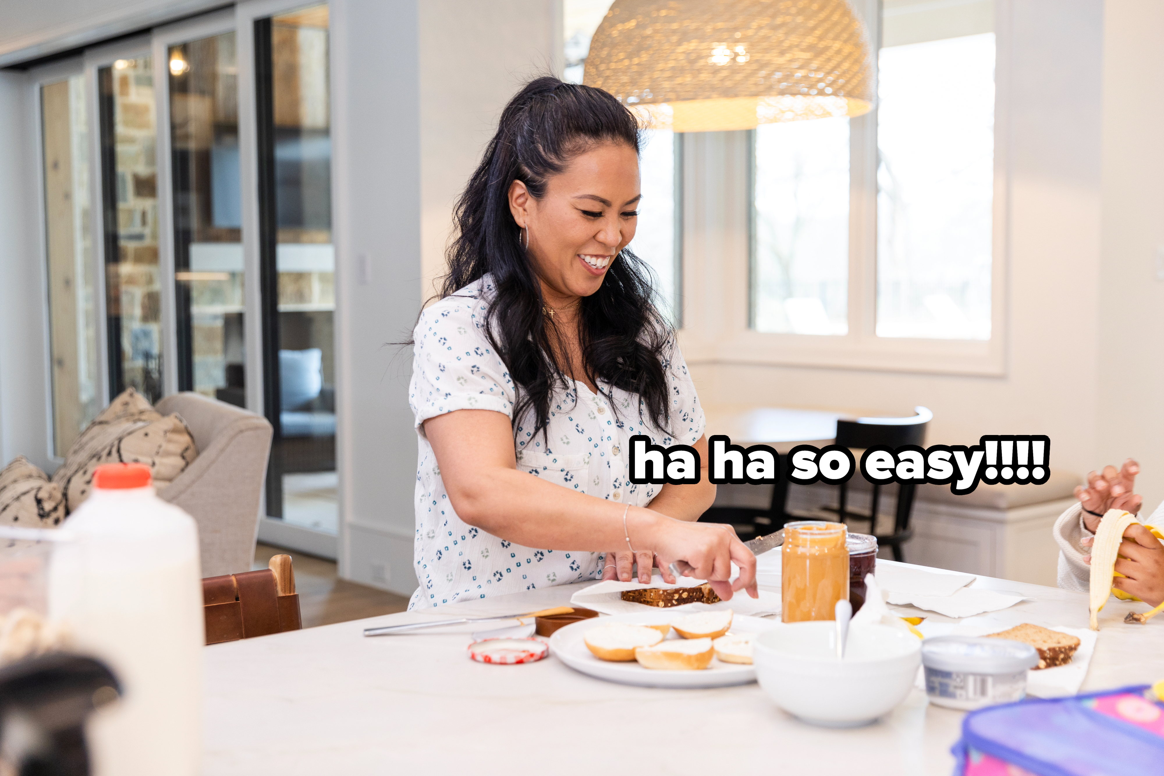 Woman smiling, preparing sandwiches in a home kitchen, various ingredients on counter
