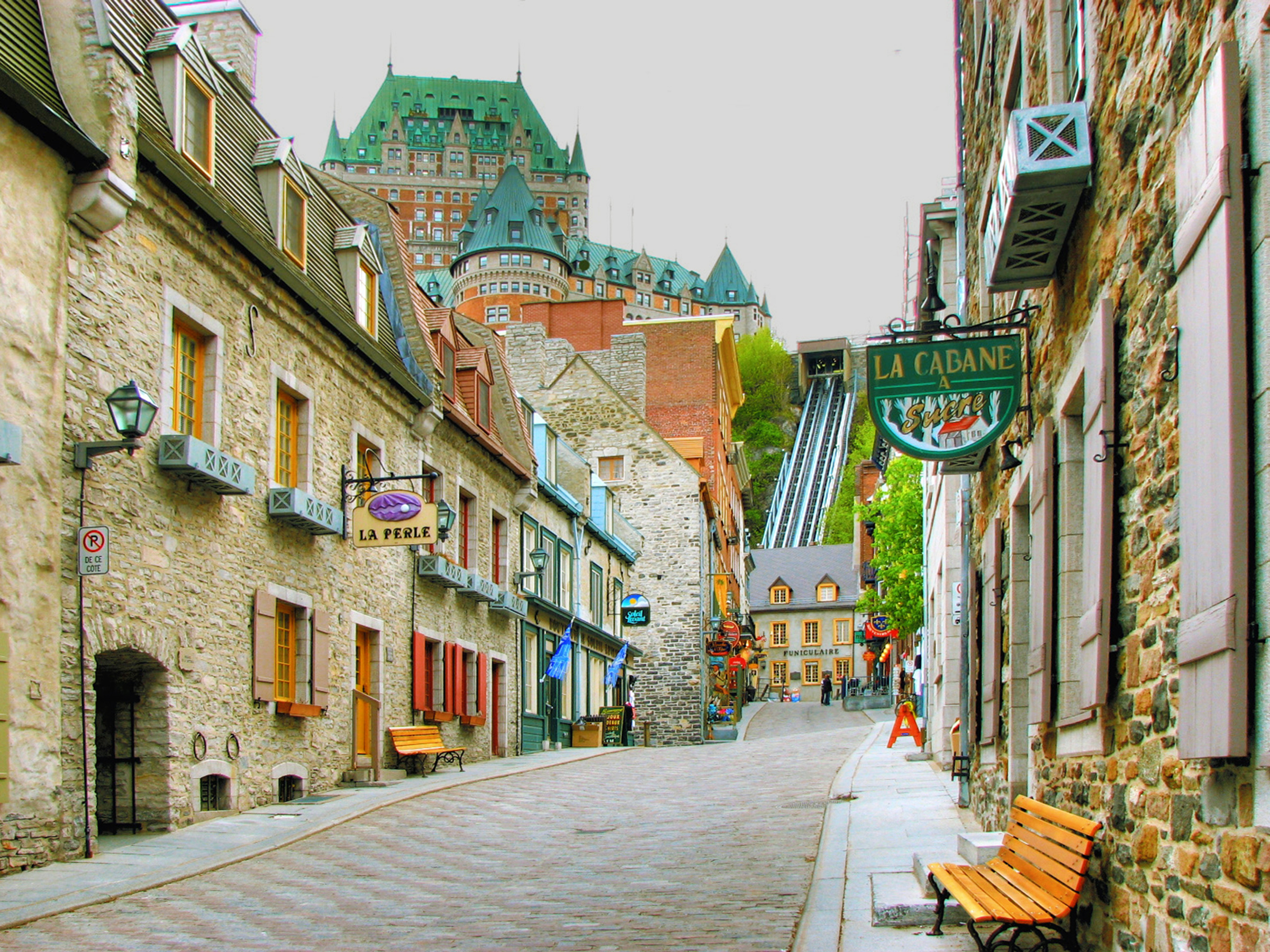 Cobblestone street in Quebec with historical buildings and Château Frontenac in the distance
