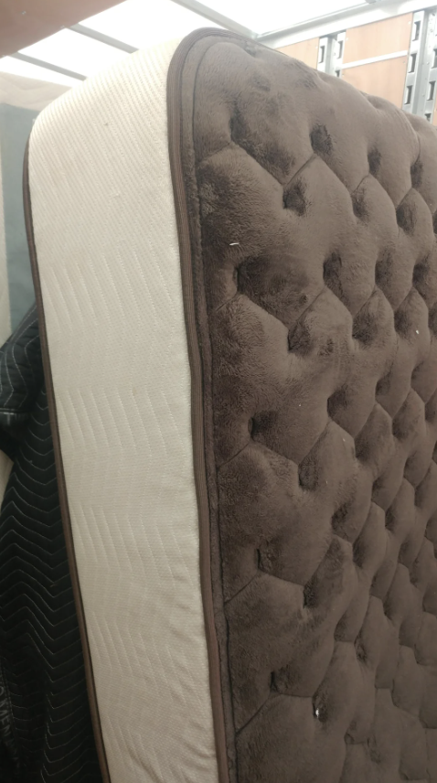 A mattress standing vertically with a patterned side and a plain side