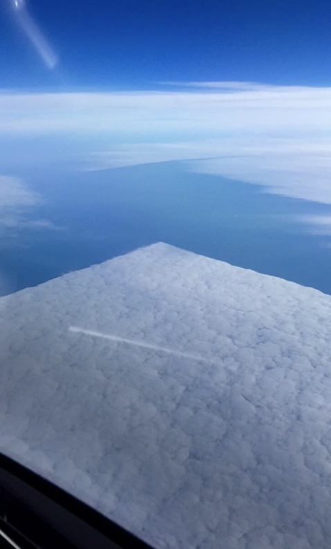 View from an airplane window showing cloud coverage and horizon